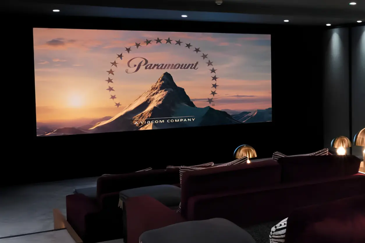 Home theater with a large screen displaying the Paramount logo. Plush seating faces the screen, and ambient lighting adds a cozy atmosphere.
